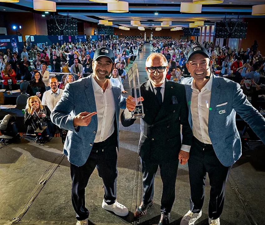 Orlando y Daniel Montiel con Emilio Estefan Jr. en un evento de C5, con el salón lleno de agentes